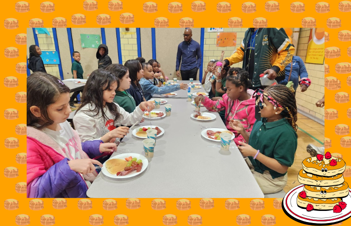  Students seated at lunchroom tables eating pancakes